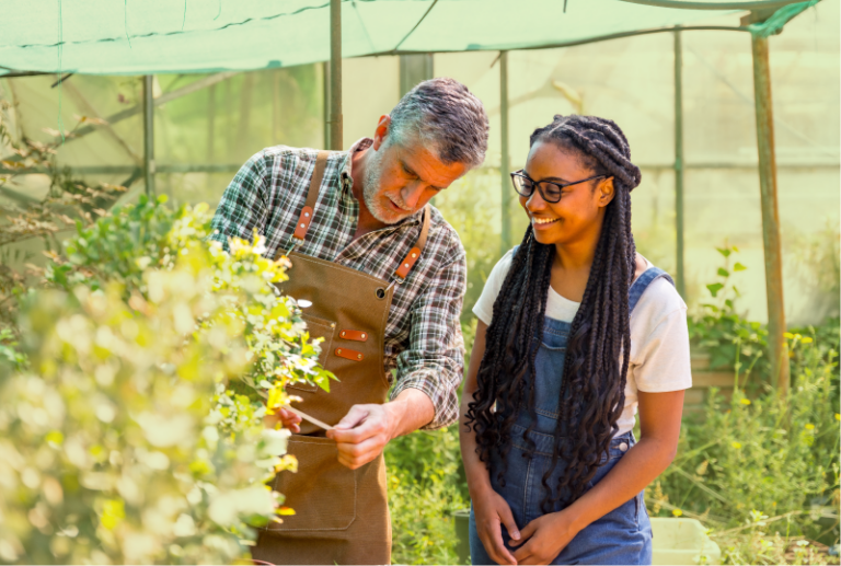 An employee is training a volunteer worker in a garden centre.