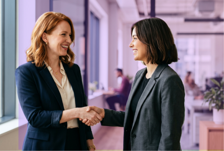 An manager and leader are smiling and shaking hands after a positive performance review.