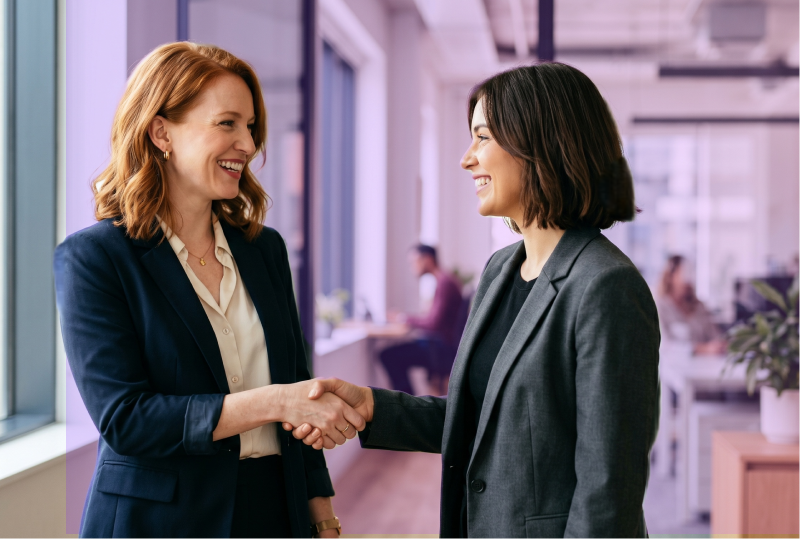 An manager and leader are smiling and shaking hands after a positive performance review.