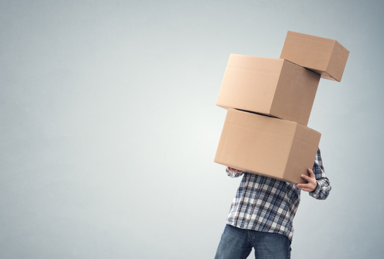 A person holding 3 boxes that go past the head and one box is falling