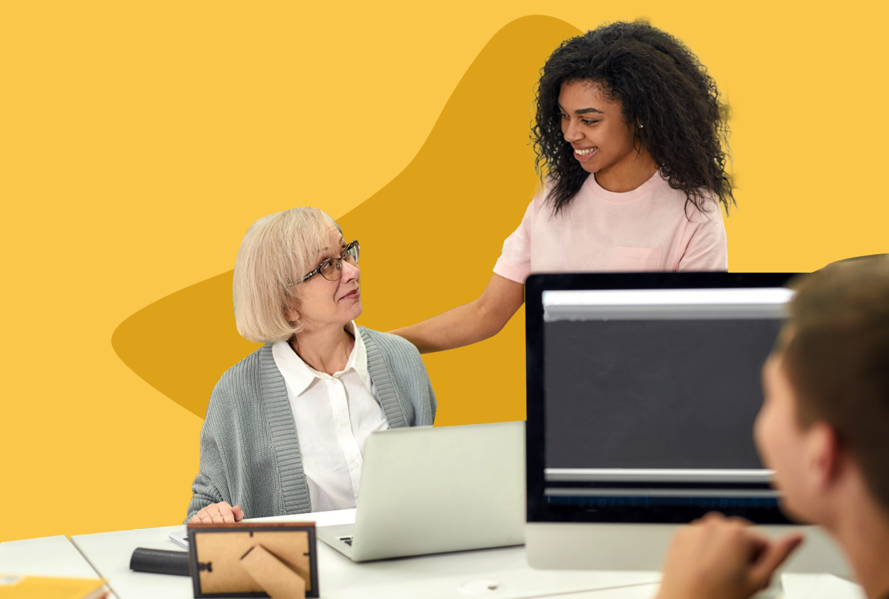 Younger employee supporting a senior employee with a laptop.