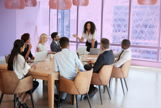 Group of employees are sitting around a table in a board room, discussing recession planning.