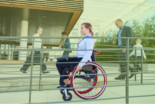 An employee in a wheelchair is going to their workplace using a ramp