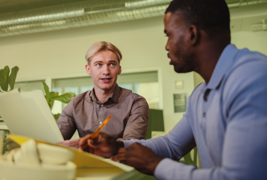 Two employees are sitting at a desk reviewing their paid time off policy together.