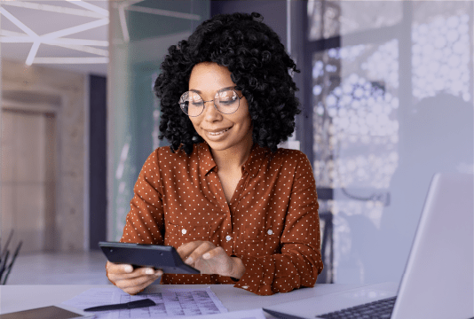 An employee is sitting at their desk and looking at a tablet.
