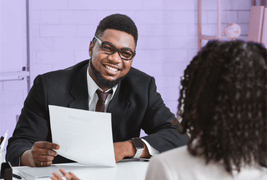 Two employees are discussing a PIP across a desk and smiling