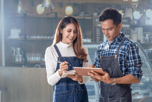Talent Management Strategies: two young employees are reviewing an ipad together and look happy with what they see