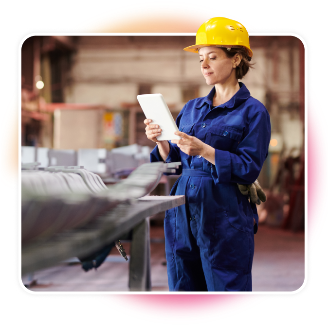 Woman looking at a tablet in a jumpsuit and hard helemt.