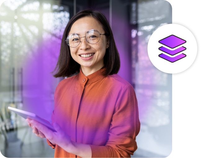 Woman smiling at camera while holding a tablet in an office.