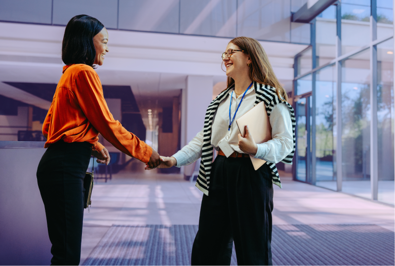 A new employee is being greeted on their first day at work in an office lobby