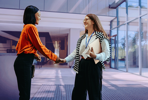 A new employee is being greeted on their first day at work in an office lobby