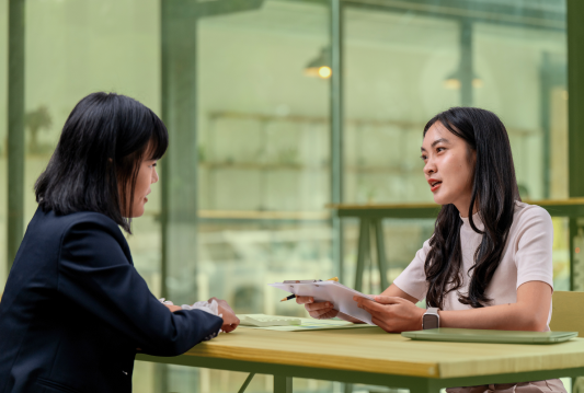 A manager is at their desk, terminating an employee sitting across the desk from them