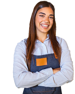 A retail worker is wearing an apron and smiling with their arms crossed.