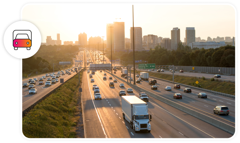 A transport truck is driving away from a city on a highway during morning rush hour traffic