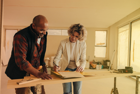 A contractor and visitor are working on a construction site.