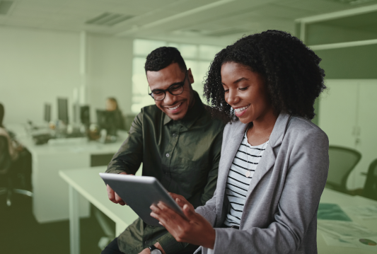 Two employees are working on a checklist for new employment legislation, such as WHMIS and Ontario's Working for Workers Acts.