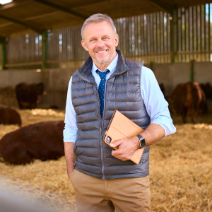 Construction manager smiling in front of barn structure
