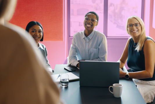 Three employees are receiving onboarding training from one trainer in a meeting room.
