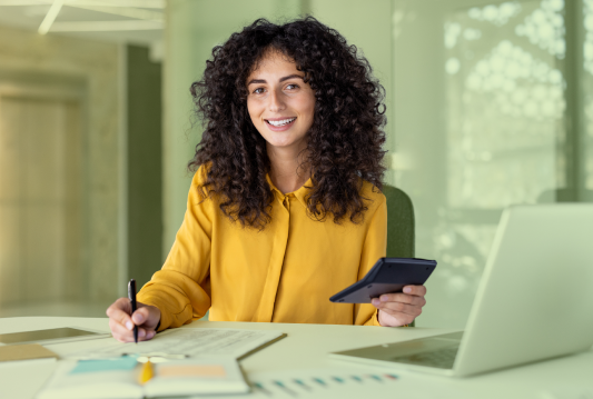 An employee is sitting at their desk and looking at a tablet.