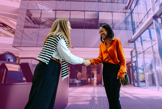 An hiring manager is meeting a new hire for the first time in an office lobby.