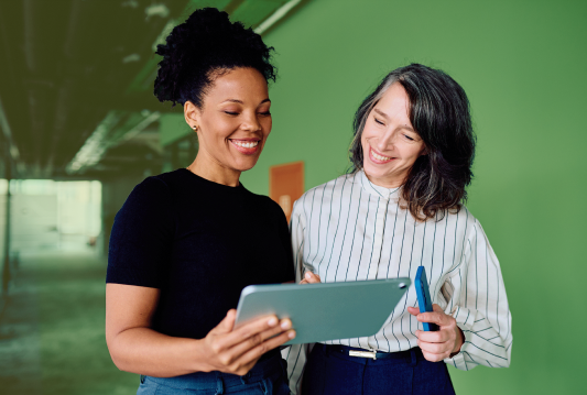 Two employees are standing next to each other, looking at an HR compliance document.