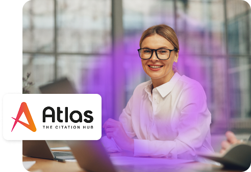 A woman smiling at a desk with the Atlas logo.