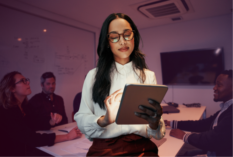 An employee is using AI in their HR role using a tablet, standing in an office board room.