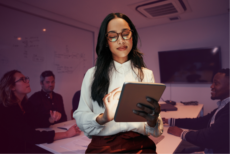 An employee is using AI in their HR role using a tablet, standing in an office board room.